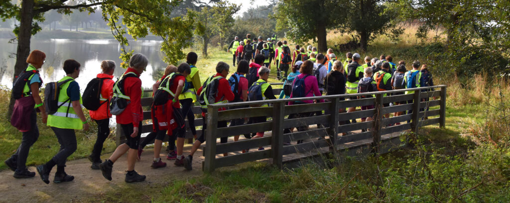 Belle image d'une centaine de marcheurs Audax traversant un pont.