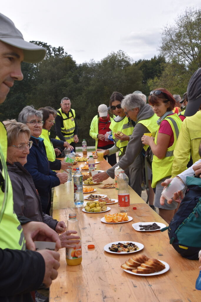 Photo de marcheurs au ravitaillement. Jus de fruit, gâteaux ou fruits secs sont sur une table.